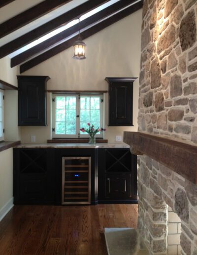 A cozy kitchen corner featuring dark wood cabinets, a stone wall, and a window overlooking greenery.