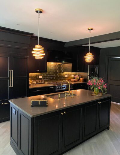 Modern kitchen with black cabinetry, gold accents, and pendant lighting.