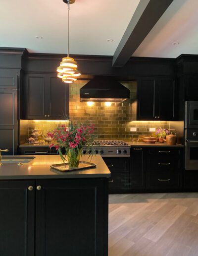 Modern kitchen with black cabinetry, stainless steel appliances, and a bouquet of pink flowers on the island.