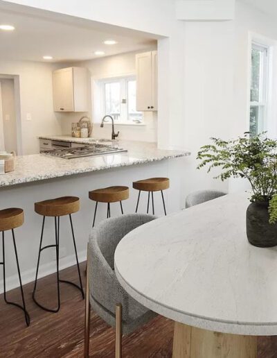 Modern kitchen interior with a central island, bar stools, and an attached dining area.