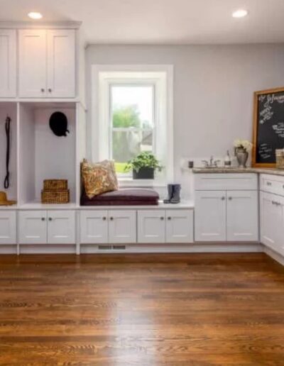 A bright, clean kitchen nook with white cabinetry, a built-in bench, and hardwood flooring.