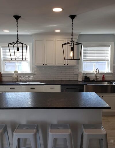 Modern kitchen with white cabinetry, subway tile backsplash, and a dark countertop island with seating.