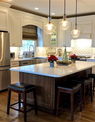 A modern kitchen with stainless steel appliances, white cabinetry, and a central island with bar stools.