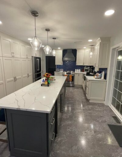 Modern kitchen interior with white cabinetry, a central island, and stainless steel appliances.