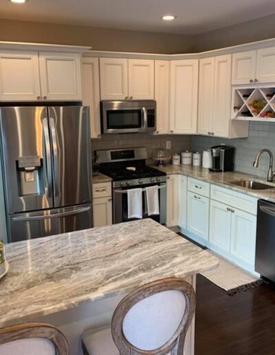 A modern kitchen with stainless steel appliances, white cabinetry, and granite countertops.