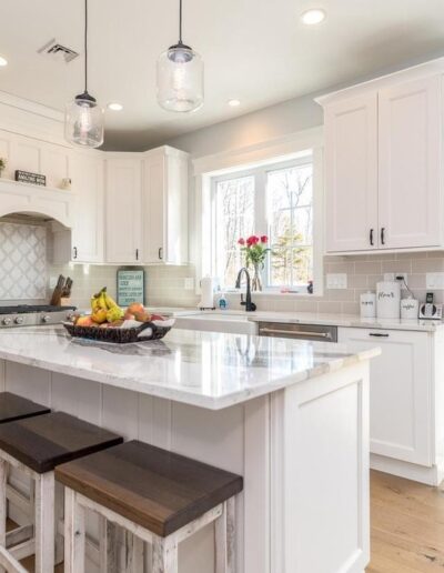 Bright kitchen with white cabinetry, central island, and pendant lighting.