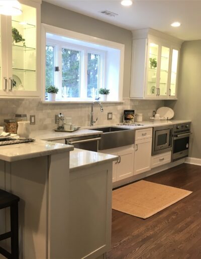 Modern kitchen interior with white cabinetry, stainless steel appliances, and wood flooring.