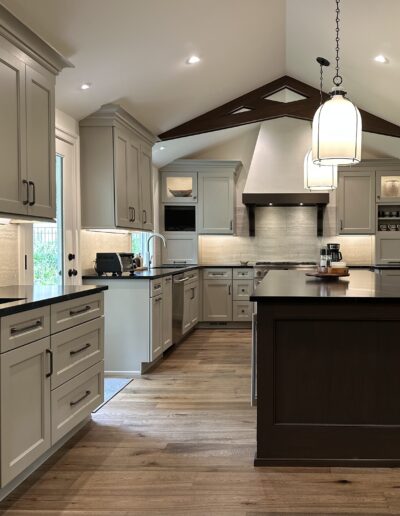 Modern kitchen interior with wooden floors, white cabinetry, a central island, and stainless steel appliances.